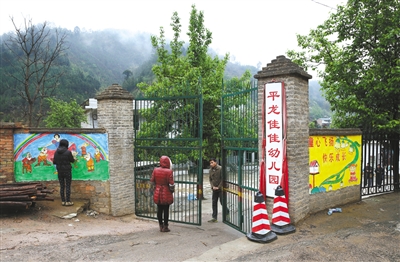 23日，云南丘北縣平龍佳佳幼兒園，死者楊梓藝的母親（中）站在幼兒園門口，園長的老公前來關門。