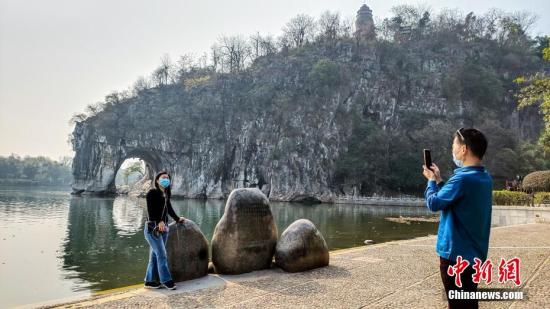 2月26日，廣西桂林市象山景區(qū)正式對(duì)外恢復(fù)開放。這是廣西桂林市21日宣布該市82個(gè)A級(jí)旅游景區(qū)向國(guó)內(nèi)外疫情防控低風(fēng)險(xiǎn)地區(qū)游客有序開放的首個(gè)景區(qū)。圖為來自廣東的游客在象鼻山前拍照留念。 中新社記者 歐惠蘭 攝